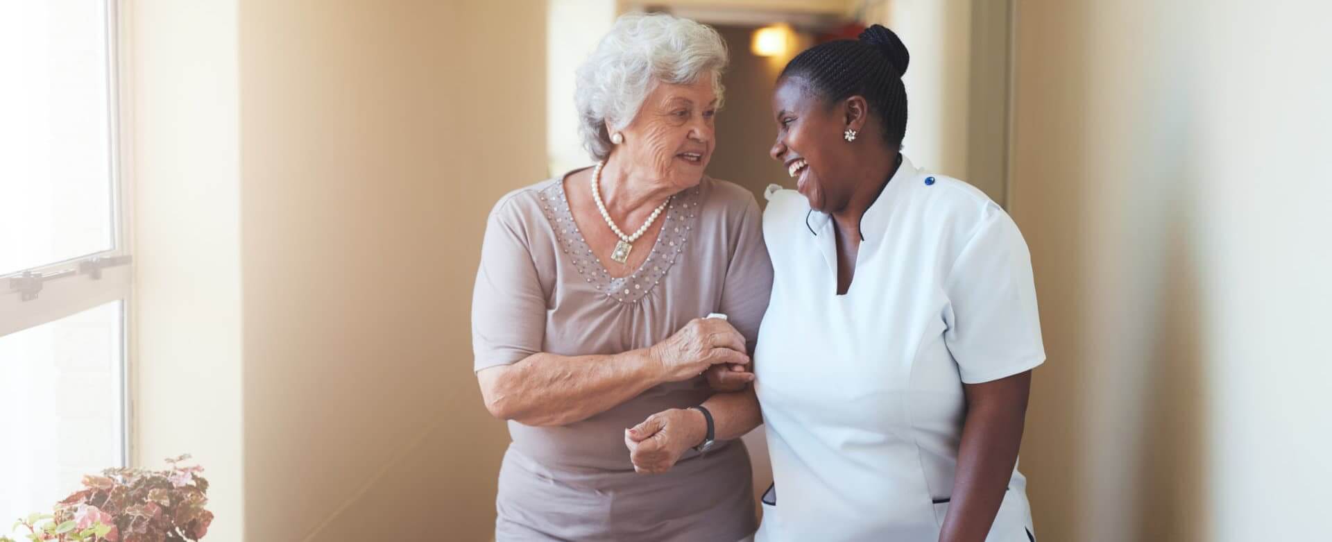 elderly smiling while holding hands with the caregiver